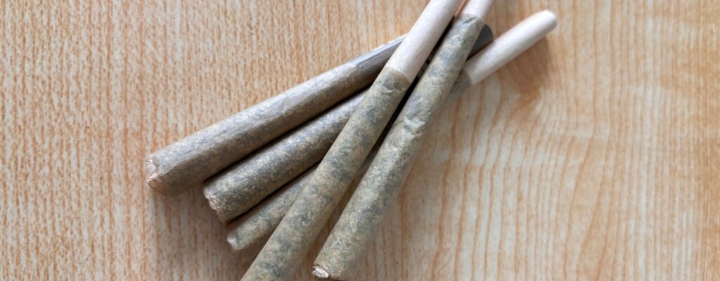 Pre-rolls on a wooden table as seen from above.